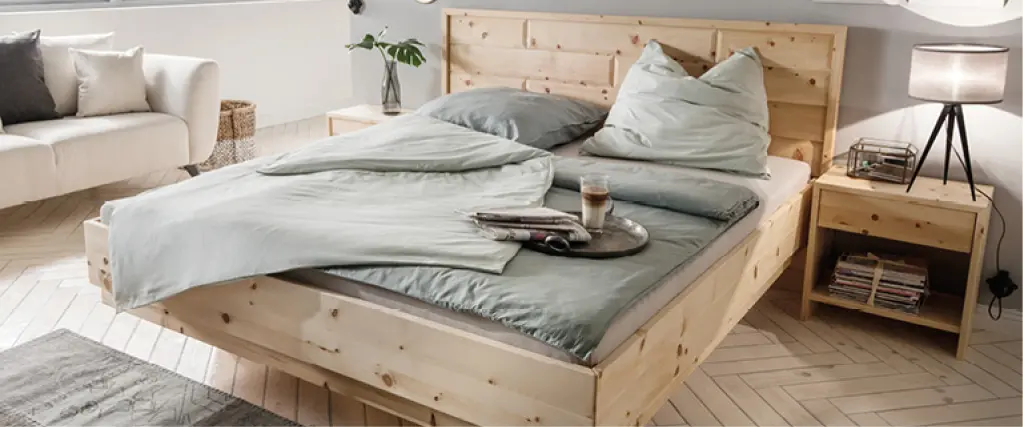 Schlafzimmer mit Massivholzbett, Nachttisch und heller Bettwäsche. Modernes Bett aus Naturholz mit gemütlicher Einrichtung und natürlicher Wohnatmosphäre
